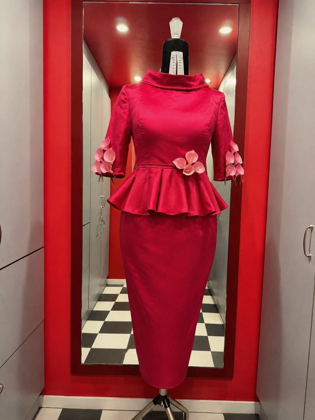 Tailleur fucsia con peplo e fiori applicati sulle maniche, esposto in vetrina